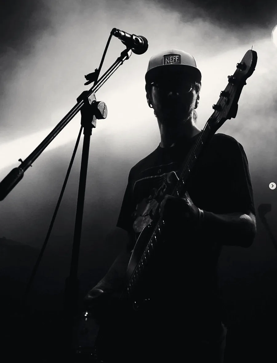 Pablo en silueta tocando el bajo, entre luces y humo