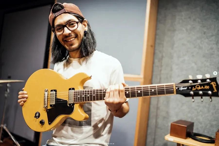 Pablo sonriendo con una guitarra Gibson amarilla en el estudio